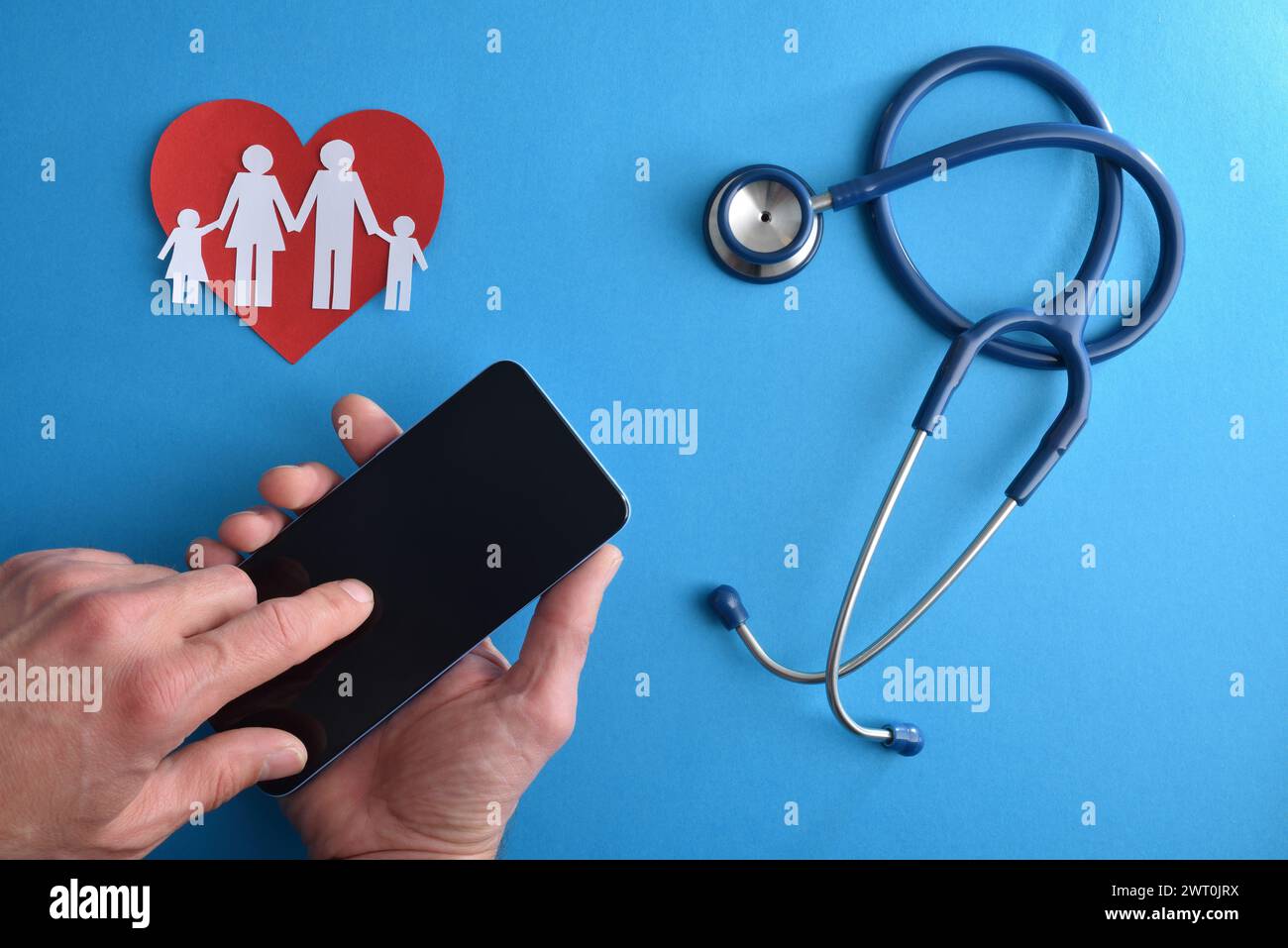 Familie Online-Gesundheitsdienst konzeptioneller Hintergrund mit Person, die Handy mit Stethoskop und Papierausschnitte der Familie auf blauem isoliertem BA verwendet Stockfoto