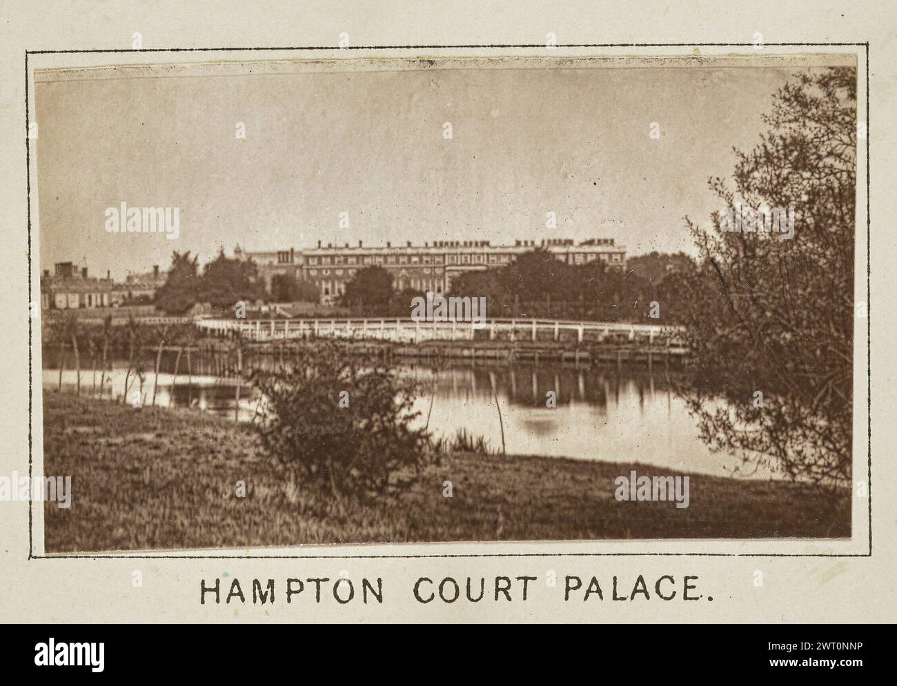 Hampton Court Palace. Henry W. Taunt, Fotograf (britischer Fotograf, 1842–1922) um 1886 eines von drei Fotos, die eine gedruckte Karte von Kingston und der Umgebung, einschließlich Hampton Court Park und Bushy Park, entlang der Themse illustrieren. Das Foto zeigt eine Fernansicht des Hampton Court Palace von der anderen Seite des Flusses. Setzlinge säumen das Flussbett im Vordergrund. (Recto, Mount) unten in der Mitte, Bild unten, in schwarzer Tinte gedruckt: 'HAMPTON COURT PALACE'. Stockfoto