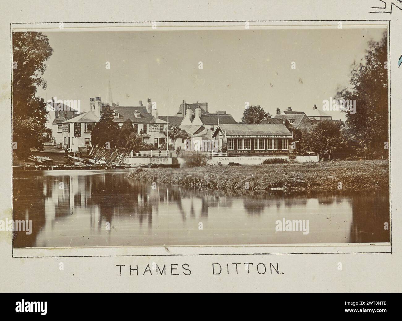 Thames Ditton. Henry W. Taunt, Fotograf (Britisch, 1842 - 1922) 1897 eines von drei Fotos mit Tippeingabe, die eine gedruckte Karte von Kingston und der Umgebung, einschließlich Hampton Court Park und Bushy Park, entlang der Themse, illustrieren. Das Foto zeigt einen Blick auf das Swan Hotel am Flussufer in Thames Ditton von der anderen Seite des Wassers. An der Bootsanlegestelle des Hotels befinden sich mehrere Boote, die an den Docks befestigt sind, und zwei Männer stehen oben auf der Treppe, die zum Wasser führt. (Recto, Mount) unten in der Mitte, unter dem Bild, in schwarzer Tinte gedruckt: „THAMES DITTON“. Stockfoto