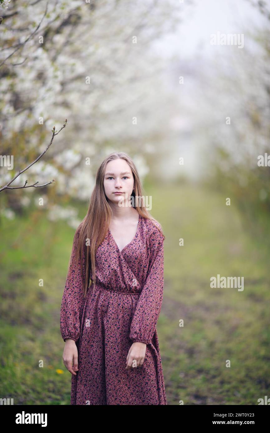 Ein Mädchen in einem blühenden Garten, das in die Kamera schaut Stockfoto