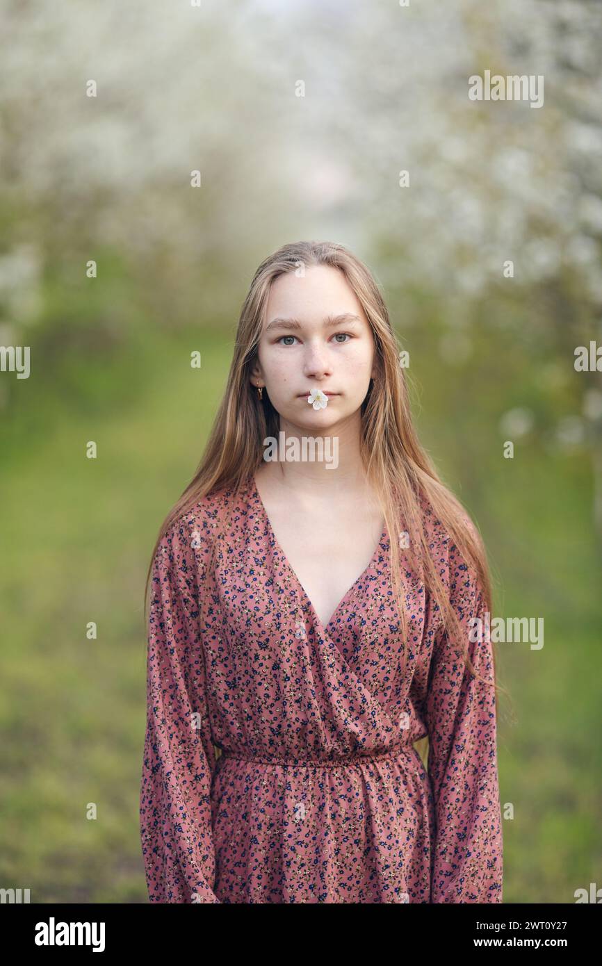 Ein Mädchen, das eine weiße Frühlingsblume in den Lippen hält Stockfoto