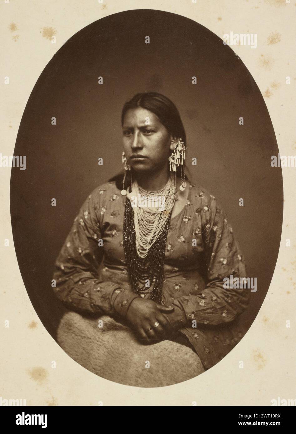 Sioux-Indianerin. H.H. Whitney, Fotograf (amerikanisch, aktiv im 19. Jahrhundert) 1860–1880 Porträt einer sitzenden Sioux-Indianerin. Sie hat mehrere Perlenstränge um ihren Hals und hat beide Hände im Schoß. (Rückseitig, Halterung) links unten, Bleistift: 'Sioux Squaw'; Stockfoto Sioux-Indianerin. H.H. Whitney, Fotograf (amerikanisch, aktiv im 19. Jahrhundert) 1860–1880 Porträt einer sitzenden Sioux-Indianerin. Sie hat mehrere Perlenstränge um ihren Hals und hat beide Hände im Schoß. (Rückseitig, Halterung) links unten, Bleistift: 'Sioux Squaw'; Stockfoto