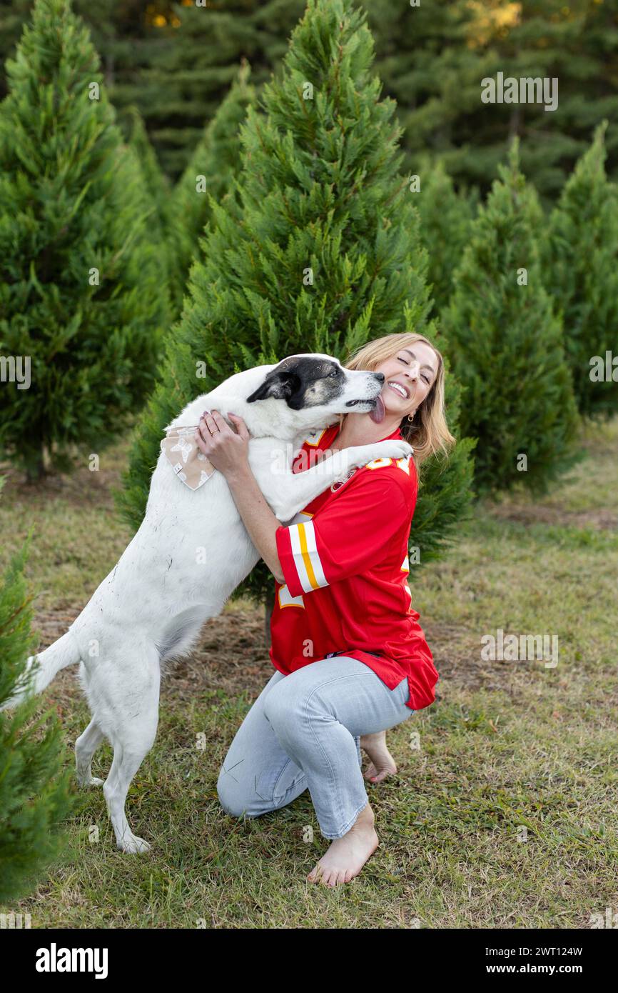 Fan im Trikot umarmt ihren Hund spielerisch Stockfoto