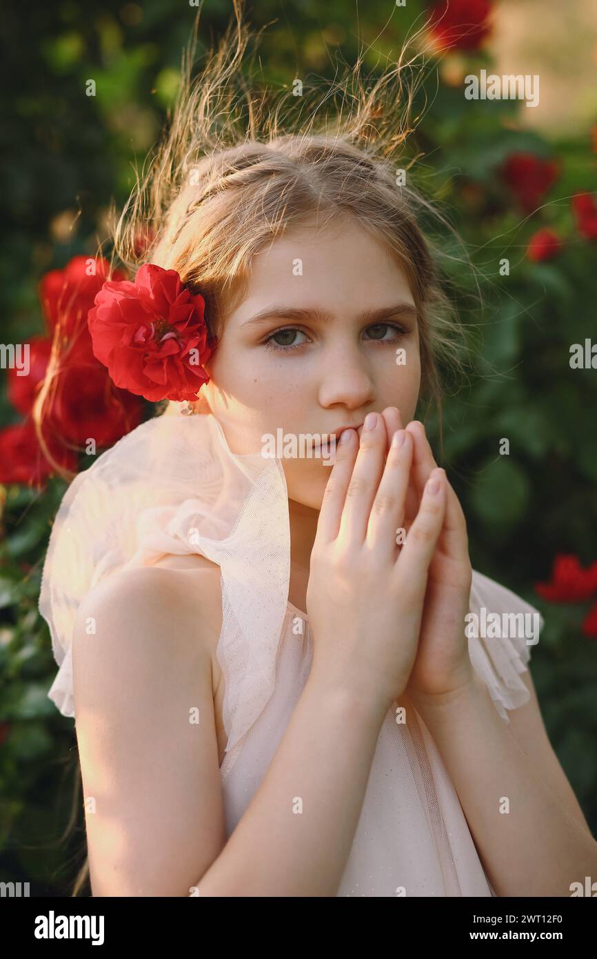 Ein junges Mädchen mit roter Rosenblume im Haar mit betender Hand Stockfoto