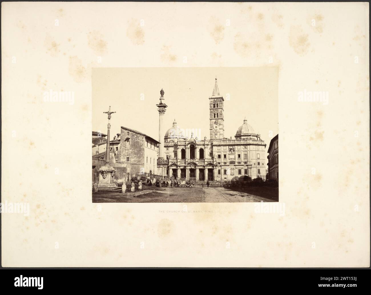 Die Kirche St.. Maria, Rom. Giorgio Sommer, Fotograf (italienisch, geb. 1834–1914) um 1860–1875 Eine Kirche mit einem spitzen Glockenturm und zwei Kuppeldächern. Vor der Kirche befinden sich zwei Säulen, von denen eine mit einer Figur und die andere mit einer Figur auf einem Kreuz gekrönt ist. Eine Gruppe Ochsen mit Karren steht vor der Kirche. (Recto, Mount) unten in der Mitte, schwarzer Buchdruck: 'DIE KIRCHE DER Heiligen MARIA, ROM.'; (Verso, Mount) unten links, Bleistift: '19 [Circled]'; unten rechts, Bleistift: „19“; Stockfoto