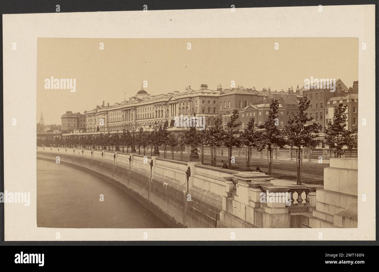 Somerset House, London. Unbekannt, Fotograf 1878–1884 Angle View of Somerset House, ein großes neoklassizistisches Gebäude mit Blick auf die Themse. Eine Steinmauer grenzt an den Fluss und entlang der Mauer ist eine Reihe von Bäumen gepflanzt. Somerset House hat ein einziges Kuppeldach, das etwas höher als der Rest des Gebäudes ist. Ein paar Männer lehnen sich an die Mauer und blicken auf den Fluss. Die Mauer entlang des Flusses ist mit Jablochkow-Kerzen gesäumt. (Verso, Mount) Mitte, Bleistift: "Somerset House/Embankment"; Stockfoto Somerset House, London. Unbekannt, Fotograf 1878–1884 Angle View of Somerset House, ein großes neoklassizistisches Gebäude mit Blick auf die Themse. Eine Steinmauer grenzt an den Fluss und entlang der Mauer ist eine Reihe von Bäumen gepflanzt. Somerset House hat ein einziges Kuppeldach, das etwas höher als der Rest des Gebäudes ist. Ein paar Männer lehnen sich an die Mauer und blicken auf den Fluss. Die Mauer entlang des Flusses ist mit Jablochkow-Kerzen gesäumt. (Verso, Mount) Mitte, Bleistift: "Somerset House/Embankment"; Stockfoto