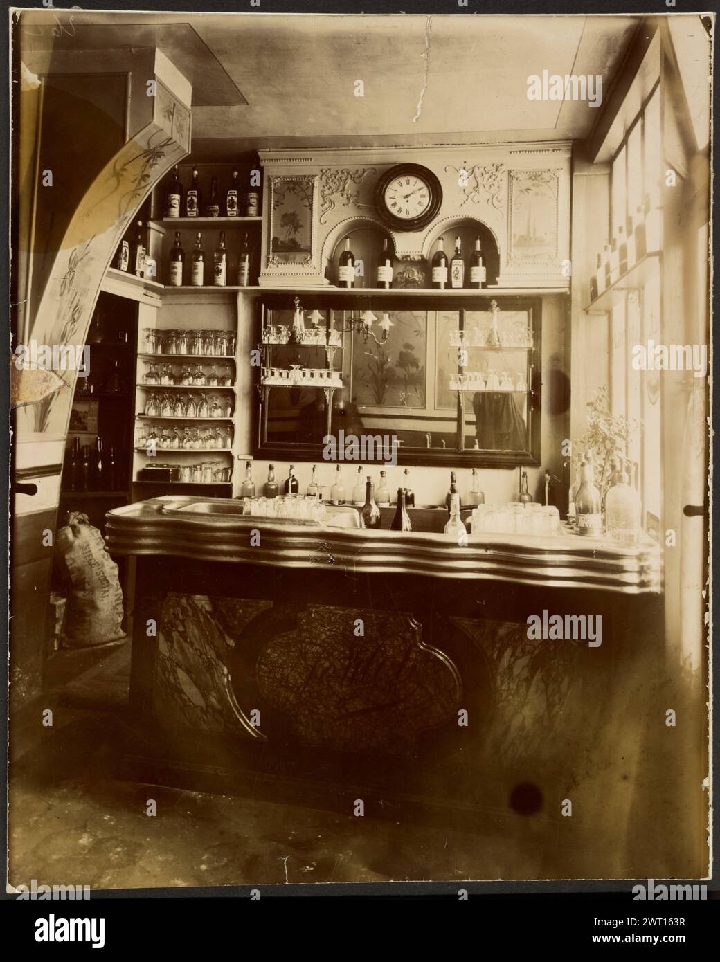 Intérieur de Café. Eugène Atget, Fotograf (Französisch, 1857 - 1927) Negativdruck 1915, Druck 1920er Jahre Bar mit Flaschen und Uhr in einem Café Sekundärbeschriftung: Inscribed verso print in the Hand of André Jammes: 'anc. coll. R.... Collaboration de l'Art Vivant'; und unleserliche Inschrift in unbekannter Hand. Stockfoto