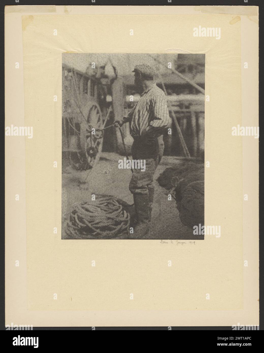 Sailor am Dock hält Seil. Doris Ulmann, Fotograf (Amerikaner, 1882–1934) 1919 Porträt eines Seemanns auf einem Dock. Sein Körper befindet sich im linken Profil, während sein Kopf nach rechts gedreht ist, was sein Gesicht behindert. Seine linke Hand ist auf seiner Hüfte, während er ein Seil in der rechten Hand hält. Seile sind zu seinen Füßen gewickelt. (Rückseitig, Montage) oben links, in rotem Bleistift: '1025a [seitlich]'; unten links, in grüner Tinte: '53 [eingekreist]'; Stockfoto