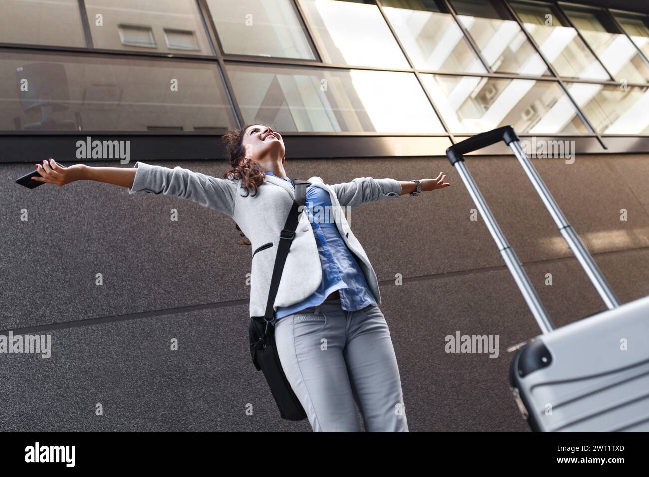 Junge Frau auf Geschäftsreise, die mit ihrem Gepäck am Flughafen läuft. Stockfoto