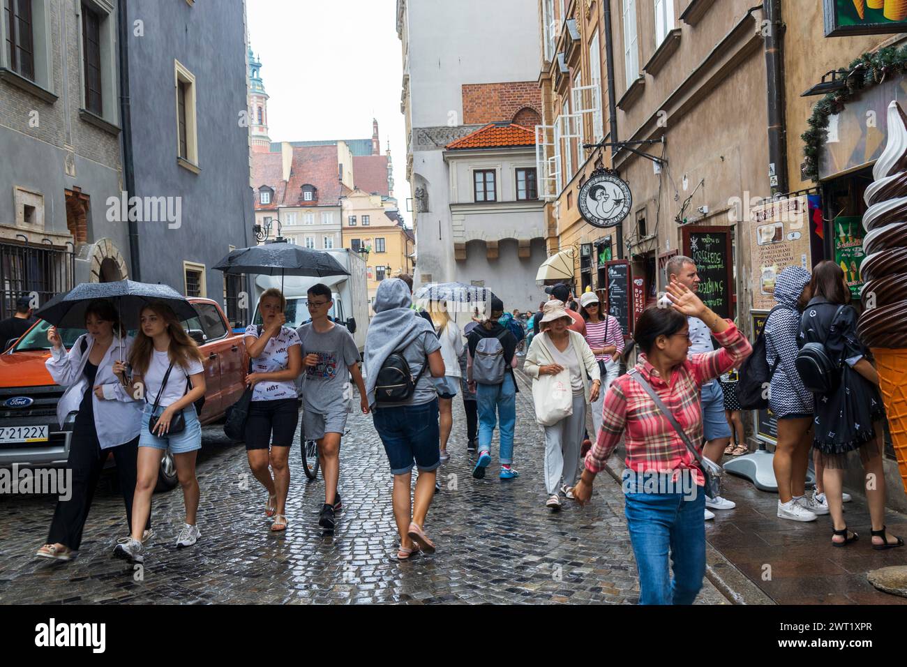 Warschau, Polen - 23. August 2023, Menschen laufen mit Regenschirmen im Regen durch die Altstadt. Stockfoto