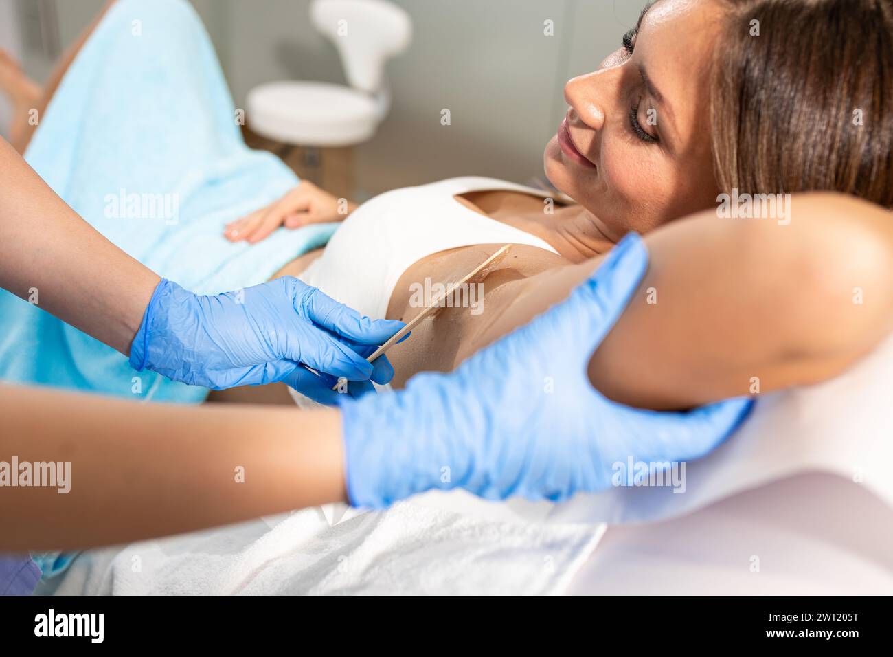 Die Frau in einem Schönheitssalon entfernt die Haare von ihrer Achselhöhle mit Laser-Epilierung. Stockfoto