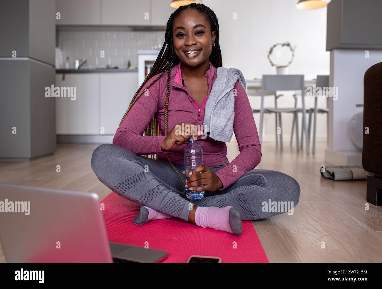 Porträt einer jungen afroamerikanerin zu Hause, die nach dem Training auf dem Boden ruht. Stockfoto