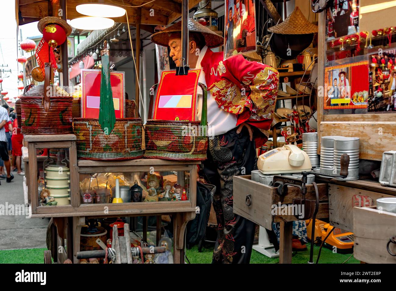 Jeden Samstag eröffnete ein Händler in traditioneller chinesischer Tracht im chinesischen Dorf Chakngeaw sein Geschäft, um gedämpfte Brötchen, Gadgets und Antiquitäten zu verkaufen. Stockfoto