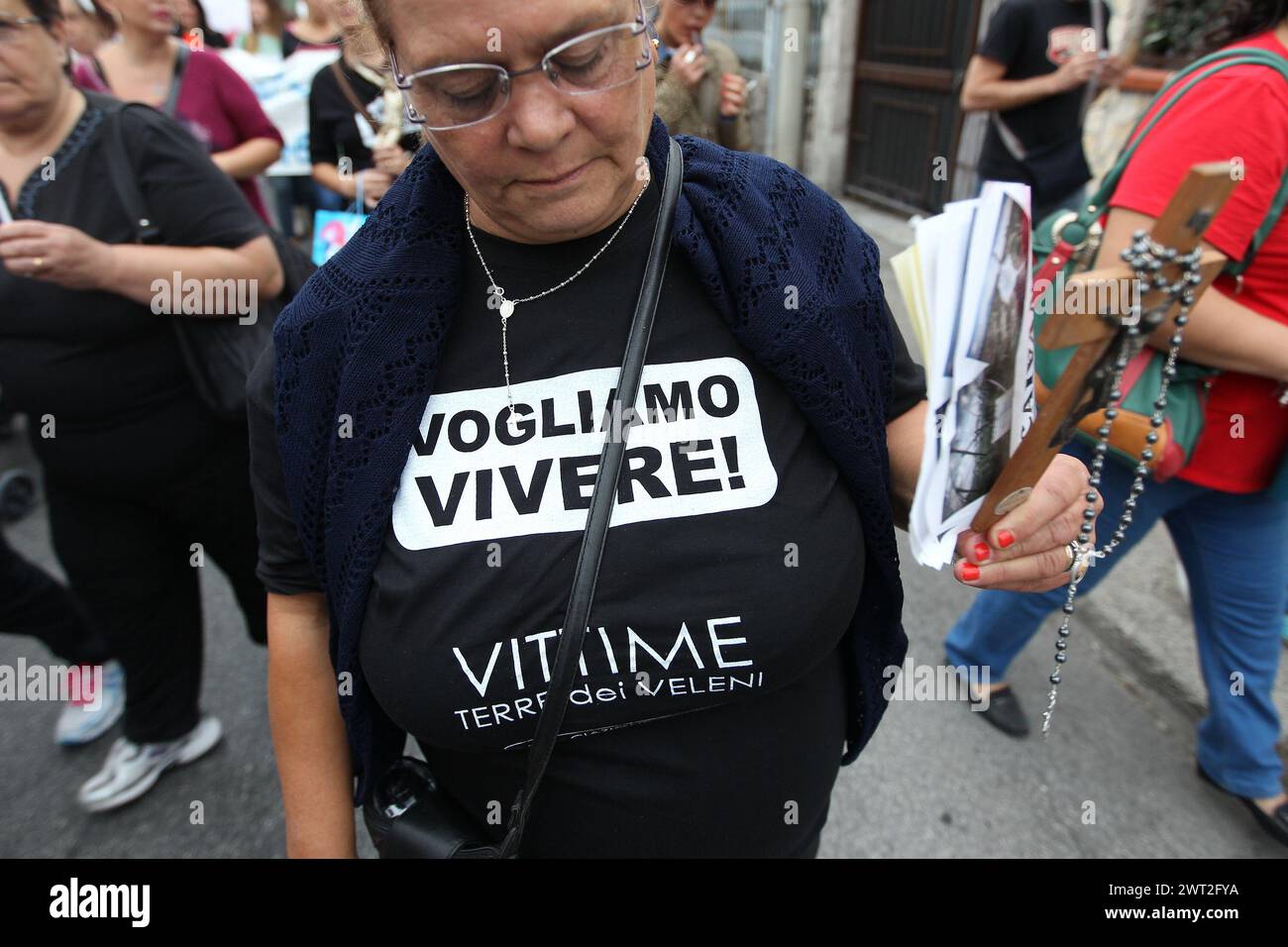 Eine Frau während der Parade der Menschen von 'Terra Dei Fuochi', die gegen die illegale Abfallentsorgung protestiert, hält ein Kruzifix in der Hand und ein T-Shirt W Stockfoto