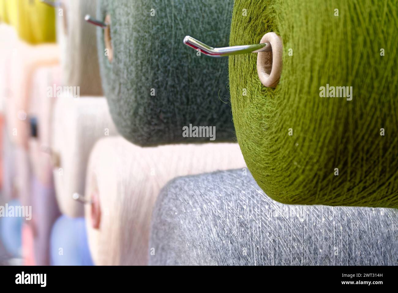 Verschiedene Spulen aus mehrfarbigen Wollfäden, abstrakter Hintergrund der Textilindustrie Stockfoto