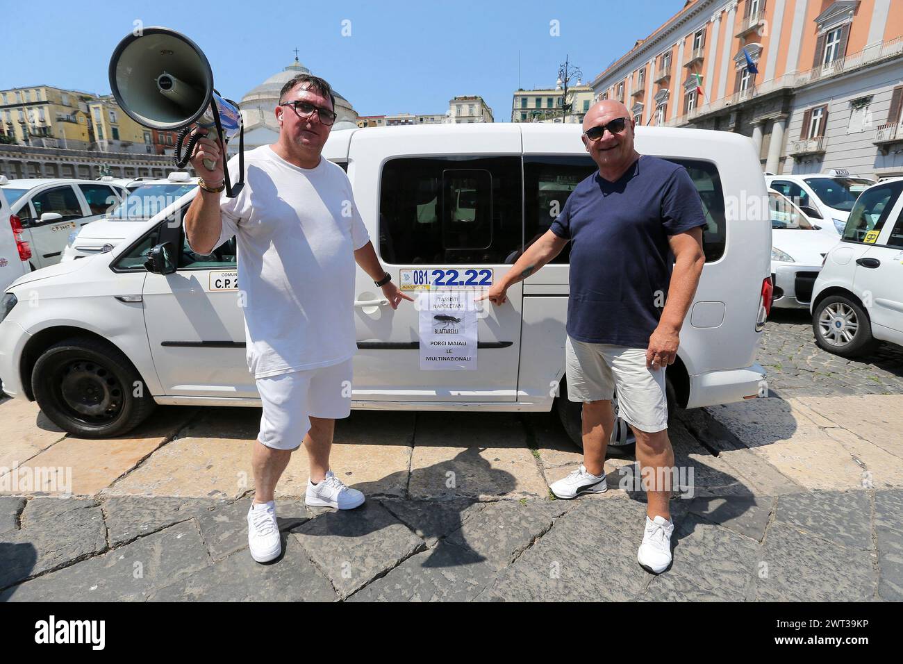 Zwei Taxifahrer zeigen auf eine Protestbroschüre auf der Piazza Plebiscito in Neapel, die von über 500 Taxis für den Protest der Taxifahrer gegen die IT besetzt ist Stockfoto