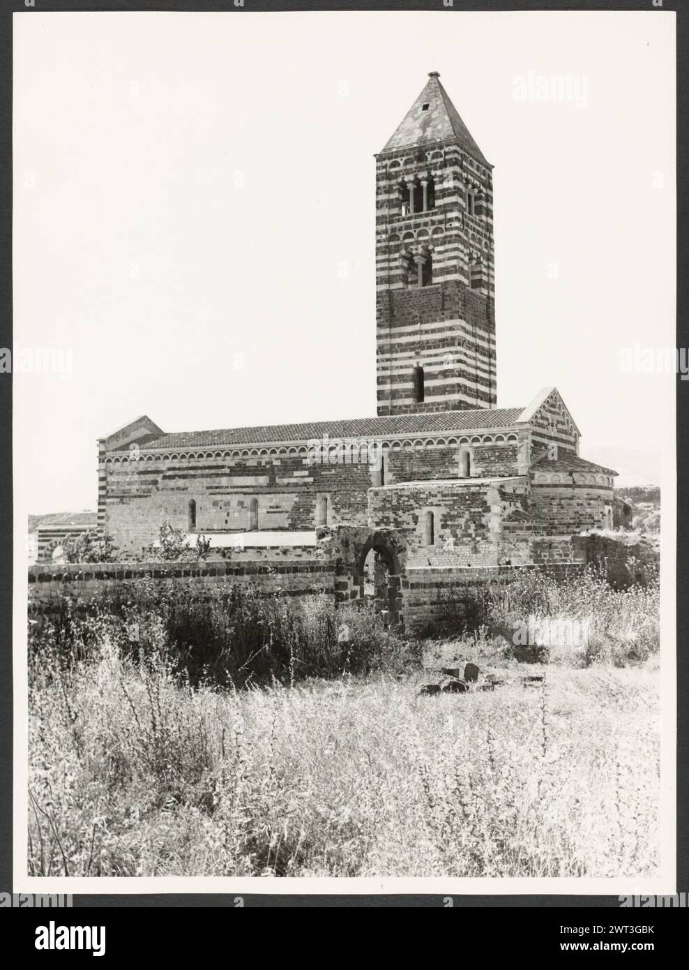 Sardinien Sassari Sassari (Environs) SS. Trinita di Saccargia (Camaldolite). Hutzel, Max 1960-1990 Außenansichten einer romanischen Kirche (12. Jahrhundert) umfassen: Eine gestreifte Fassade (dunkler Basalt und weißer Kalkstein), einen Turm mit pisanischem und lucchesischem Einfluss und verzierte/groteske Kapitelle. Antiquitäten: Zwei Säulen und Kapitelle des Portikus. Objektnotizen: Hutzel Fotokampagne Datum: 16. April 1983 der in Deutschland geborene Fotograf und Gelehrte Max Hutzel (1911–1988) fotografierte in Italien von den frühen 1960er Jahren bis zu seinem Tod. Das Ergebnis dieses Projekts, von Hutzel als Foto Arte Minore bezeichnet, ist Thorou Stockfoto