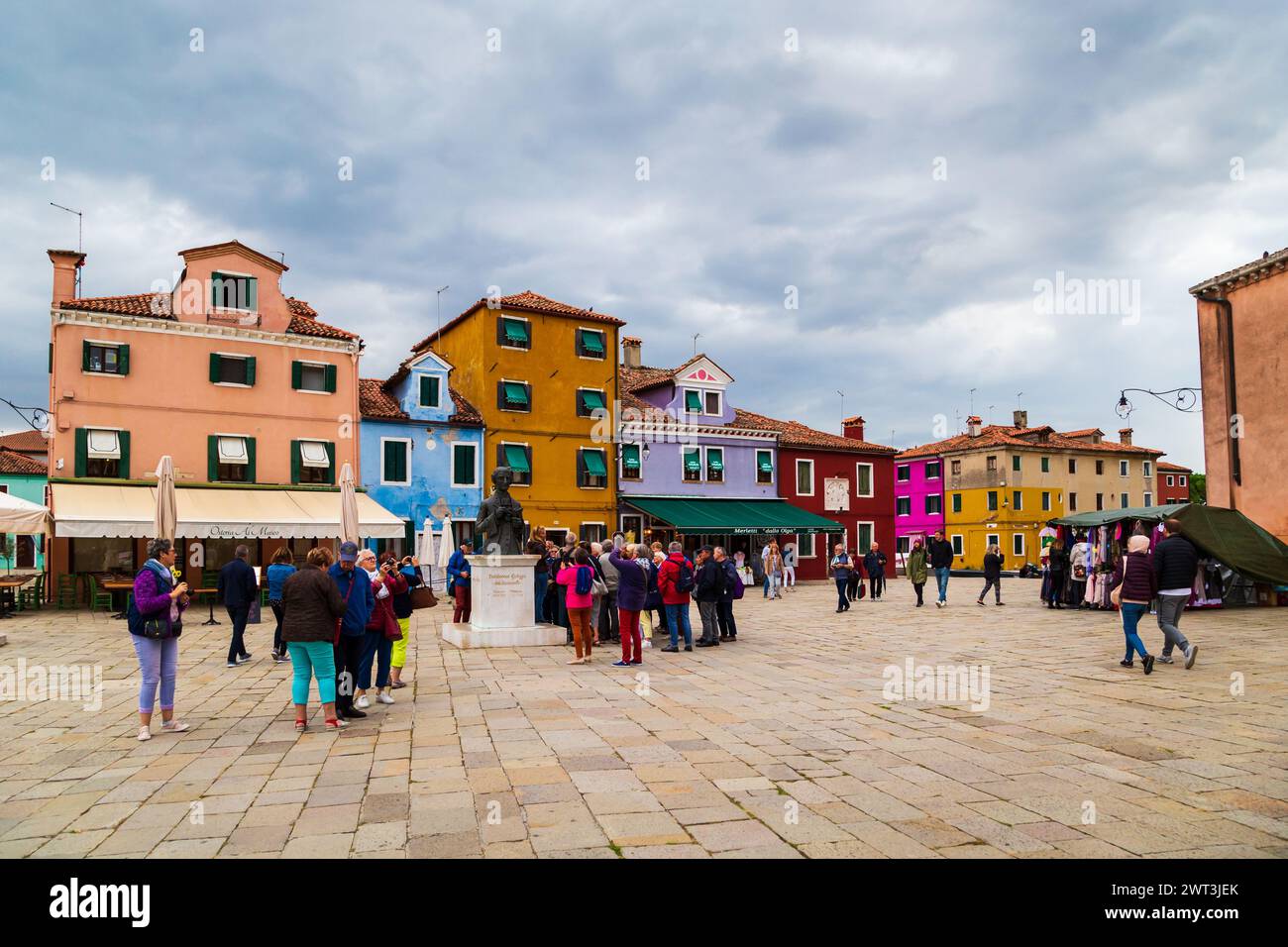 Burano, Italien - 6. Oktober 2019: Touristen in der Nähe der Statue von Baldassare Galuppi auf dem Hauptplatz von Burano, der Piazza Galuppi. Helle traditionelle farbenfrohe Gebäude auf der Insel Burano, Venedig, Italien. Stockfoto