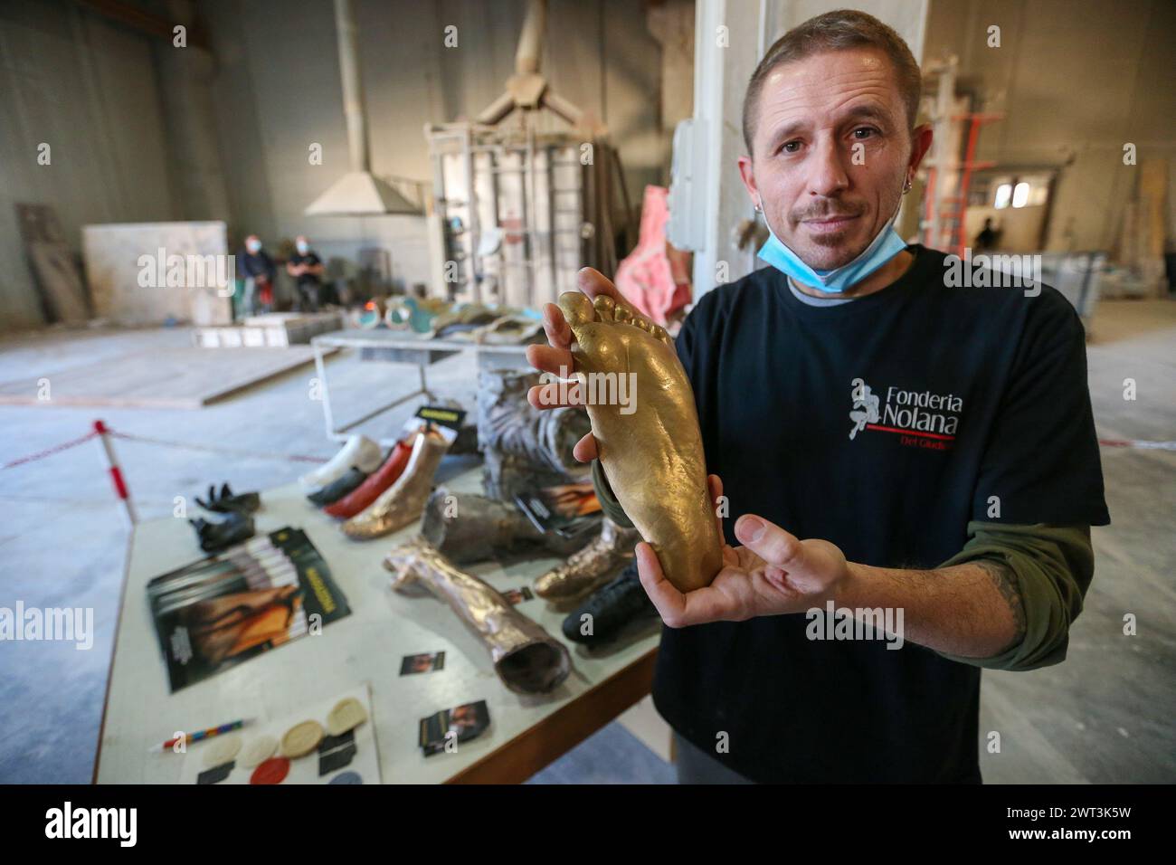 Der Bildhauer Dario Caruso mit dem Fuß der Statue von Diego Armando Maradona, während der Präsentation des Bronzegusses im Guss der Stockfoto