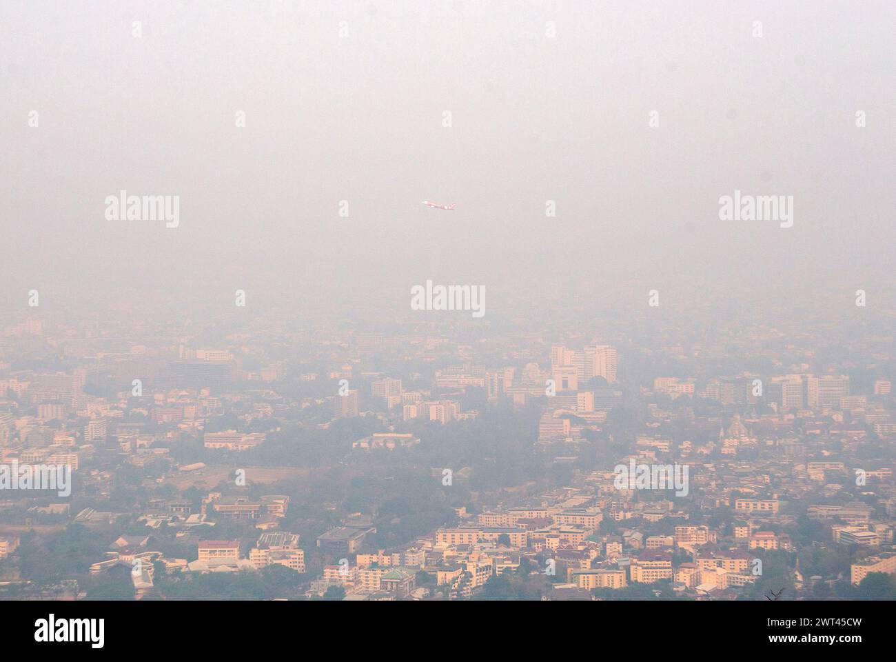 Das Flugzeug einer Air Asia Airlines fliegt über der Stadt, während es vom internationalen Flughafen Chiang Mai startet. Während des Smogs durch starke Feinstaubkonzentrationen PM2,5 trägt die Luftverschmutzung durch Waldbrände zu einer äußerst gefährlichen Luftqualität in der Stadt Chiang Mai bei. mit der gemessenen Menge an PM2,5-Staub steigt der Touristenort am 15. März 2024 zur am stärksten verschmutzten Stadt der Welt. Stockfoto