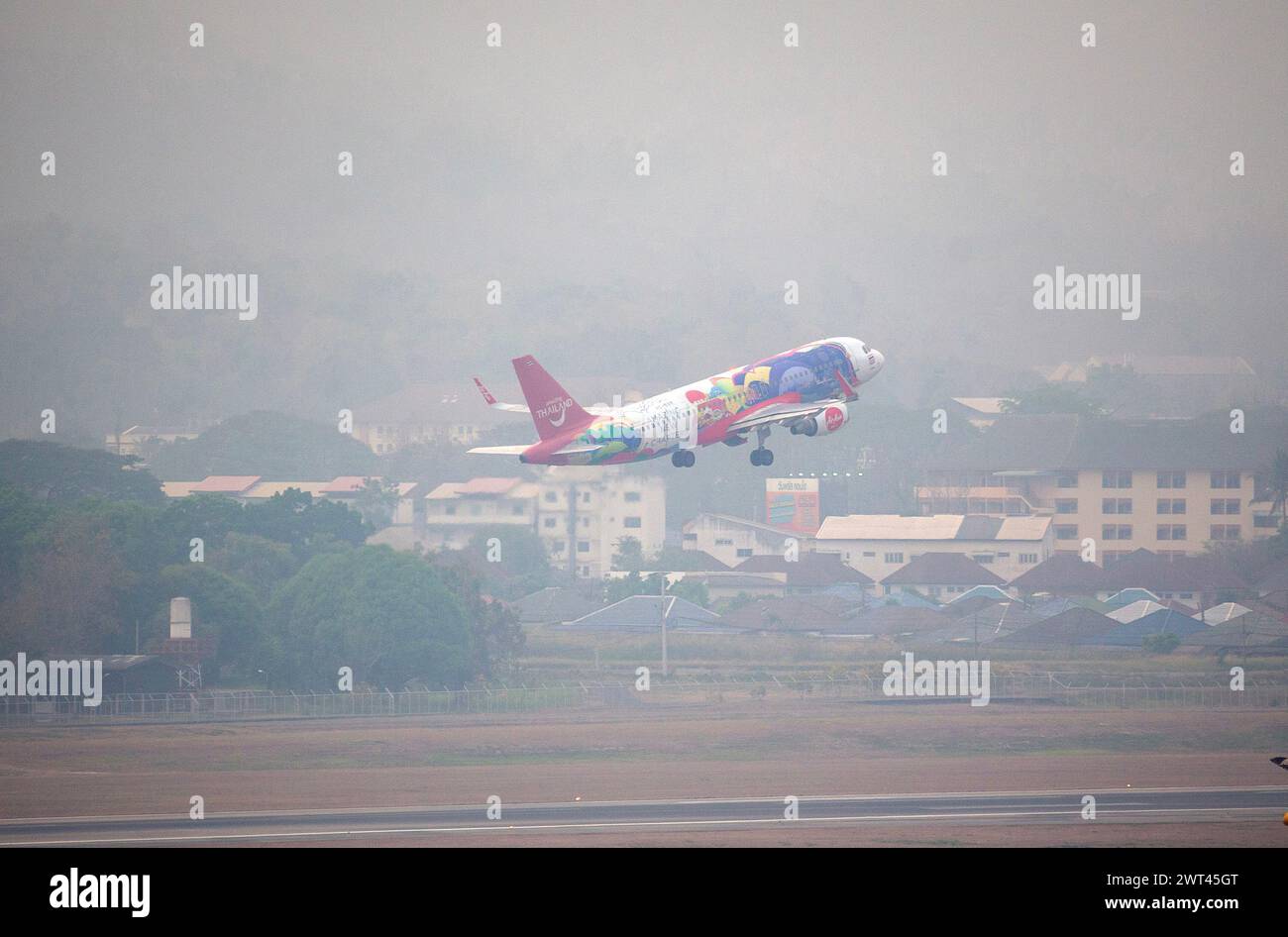 Das Flugzeug einer Air Asia Airlines startet am internationalen Flughafen Chiang Mai unter Smog aus hohen Konzentrationen von Feinstaub PM2,5. Die durch Waldbrände verursachte Luftverschmutzung trägt zu einer äußerst gefährlichen Luftqualität in der Stadt Chiang Mai bei. Die gemessene Menge an PM2,5-Staub macht die Stadt am 15. März 2024 zur am stärksten verschmutzten Stadt der Welt. Stockfoto