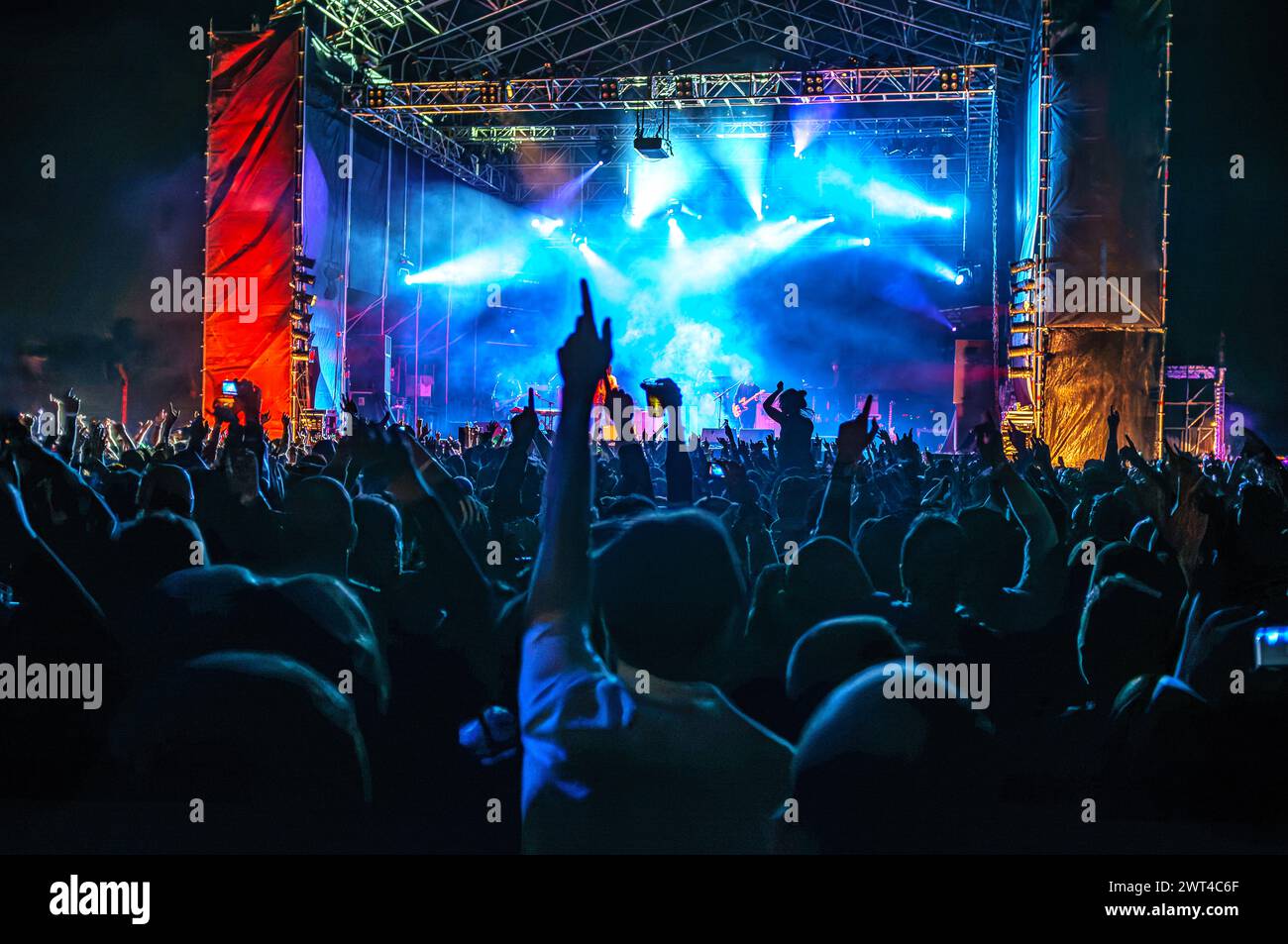 Die Menge genießt ein abendliches Rockkonzert unter leuchtenden Bühnenlichtern. Stockfoto