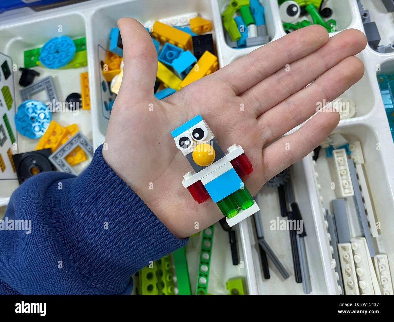 Kleine Plastikfigur aus dem Spielzeugbau-Set an der Hand des Kindes, selektiver Fokus. Konzept des Konstruktors, Blöcke Stockfoto