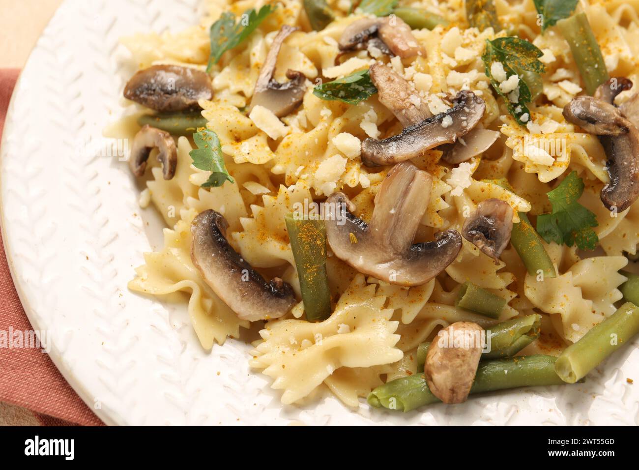 Vegetarische Pasta mit Pilzen, Petersilie, Bohnen und Käse auf weißem Teller, Nahaufnahme Stockfoto
