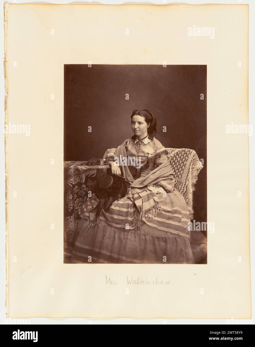 Miss Walkinshaw. Möglicherweise Thomas Rodger, Fotograf (Schottisch, 1832–1883) um 1850–1870 Ein Porträt einer jungen Frau, die auf einem kleinen Tisch sitzt und ihren Arm auflegt. Sie hält einen gefiederten Hut im Schoß und hat einen karierten Schal um ihre Schultern. (Recto, Mount) unten in der Mitte, Bleistift: „Miss Walkinshaw.“; (Verso, Mount) oben rechts, Bleistift: '34'; Stockfoto