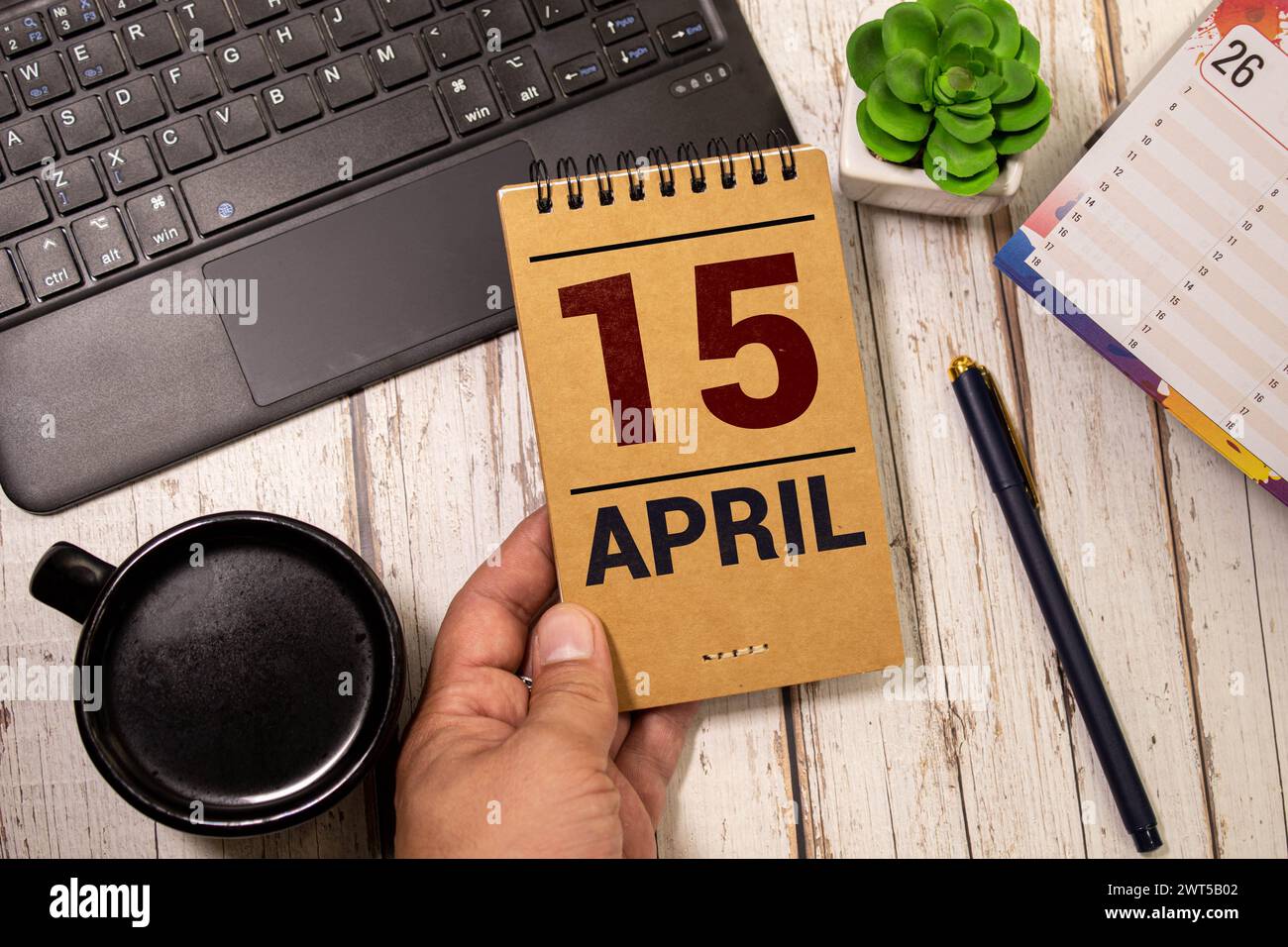 April. Tag 15 des Monats, Kalender auf Holztisch und türkisfarbenem Hintergrund. Frühlingszeit, Leerraum für Text Stockfoto