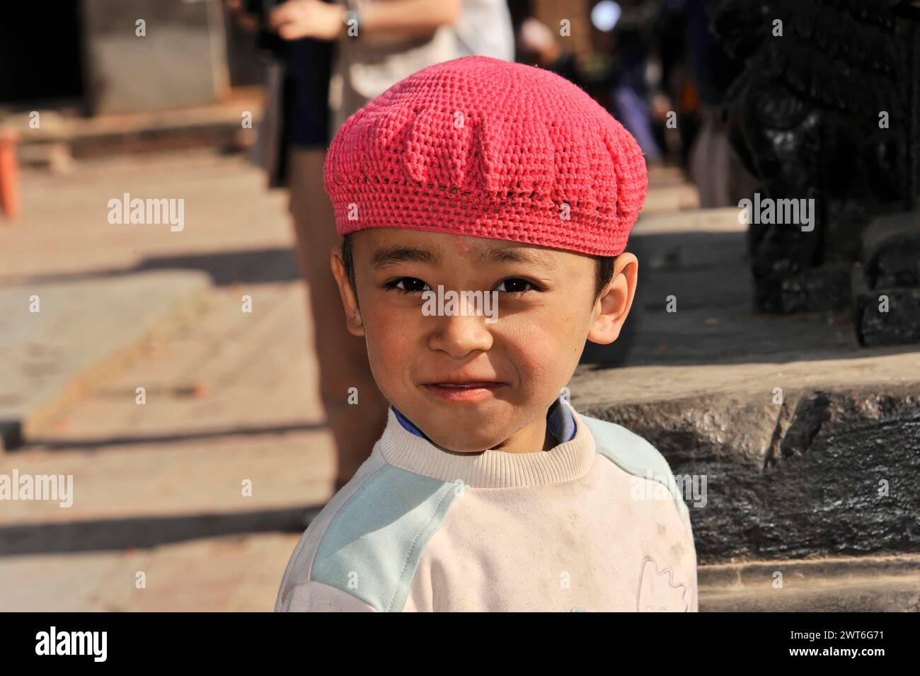 Ein Kind mit rosa Mütze sieht neugierig zur Seite, Kathmandu Valley. Kathmandu, Nepal Stockfoto