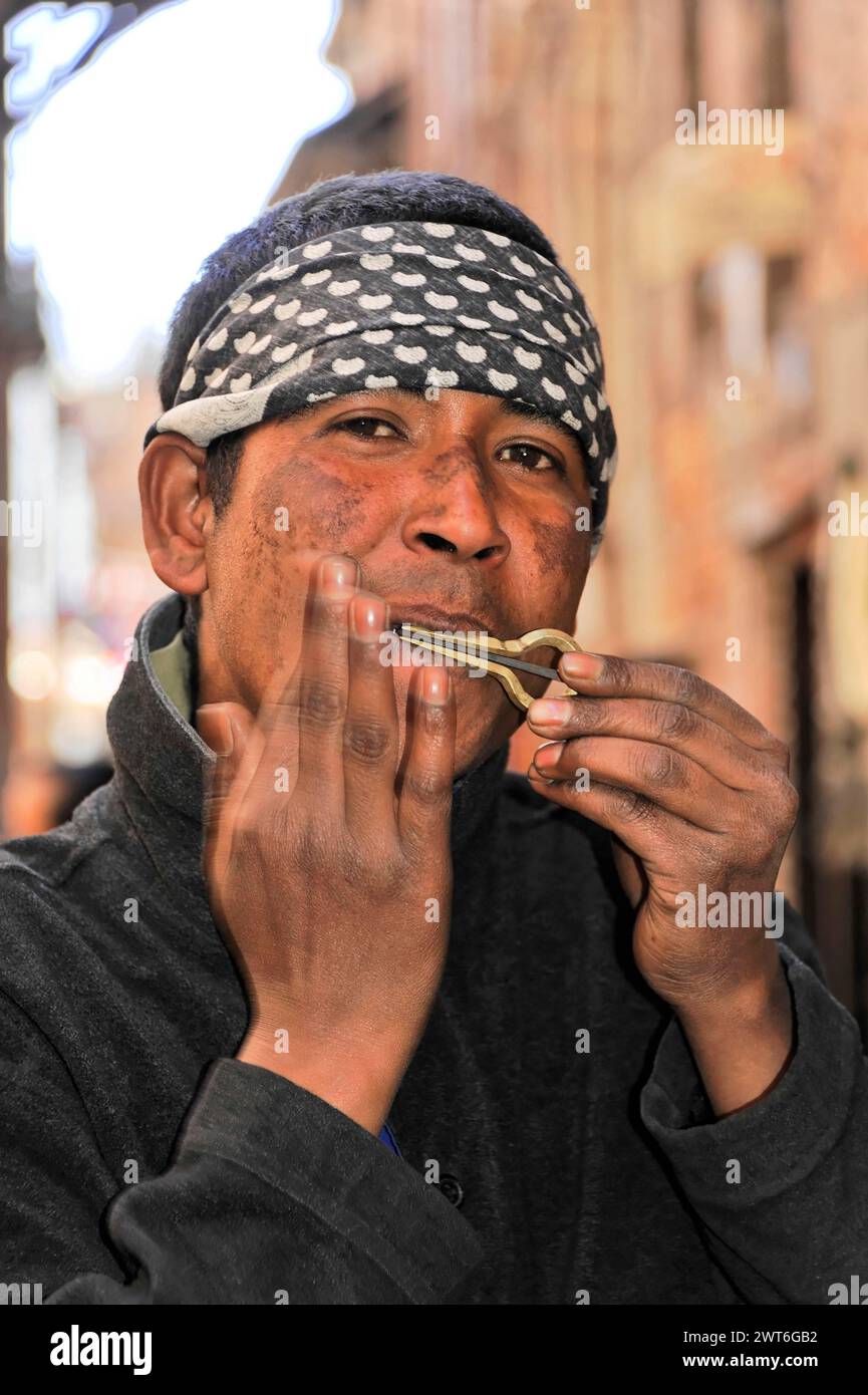 Ein Mann spielt auf der Straße die Harfe des juden, gekleidet in einem schwarz-weißen Schal, Kathmandu Valley. Kathmandu, Nepal Stockfoto