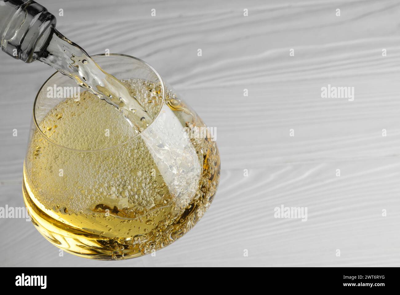 Leckerer aromatischer Wein in Glas an weißem Holztisch, Nahaufnahme. Leerzeichen für Text Stockfoto