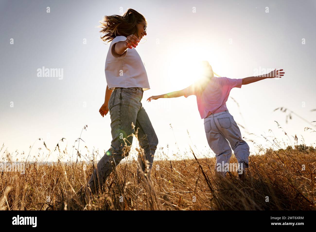Zwei fröhliche, verspielte Mädchen laufen auf dem Sunset Field Stockfoto