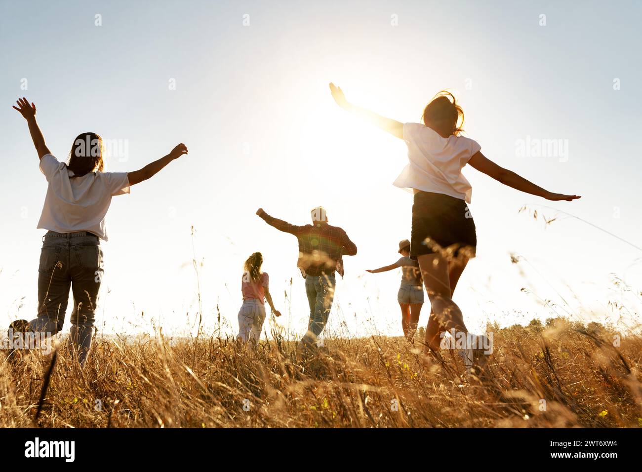 Eine Gruppe glücklicher Freunde hat Spaß und läuft auf dem Sunset Field Stockfoto