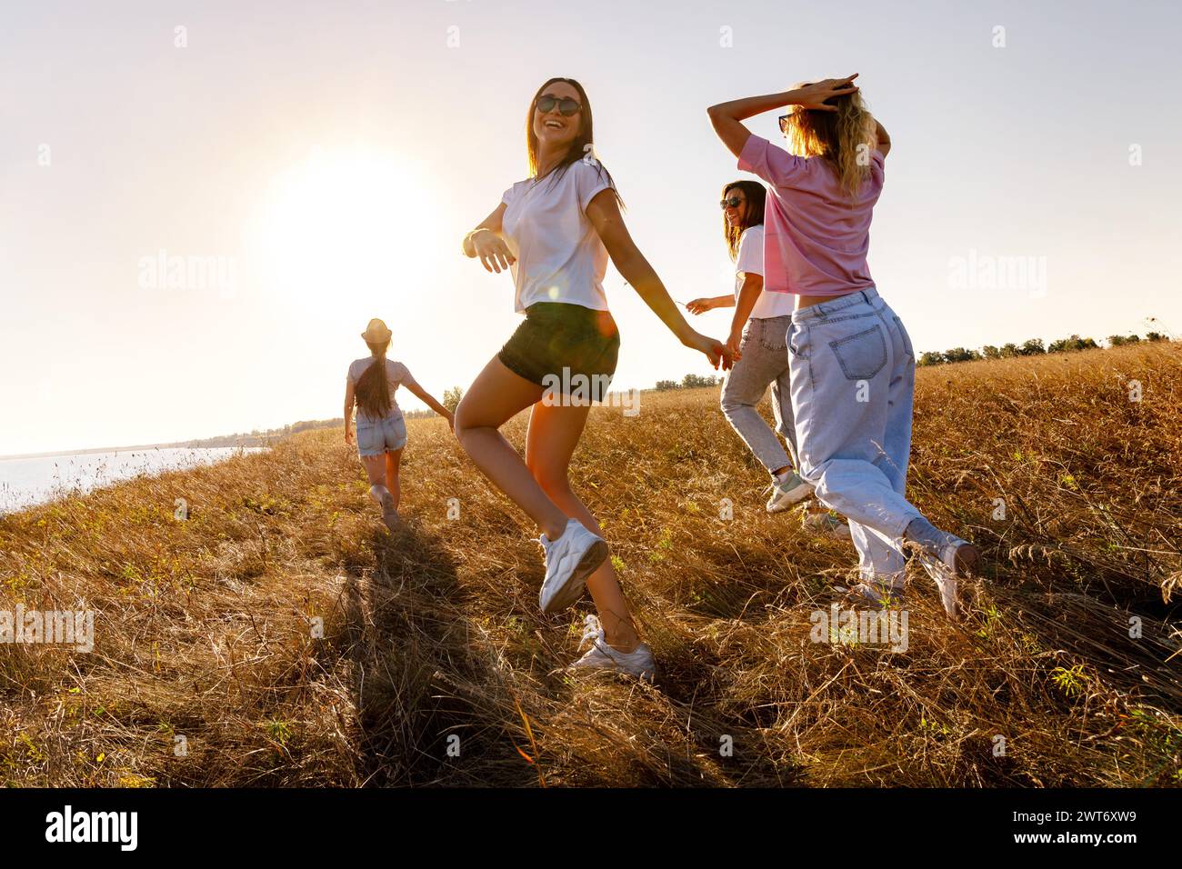 Glückliche junge Freunde haben Spaß und spazieren auf der Sonnenuntergangswiese Stockfoto
