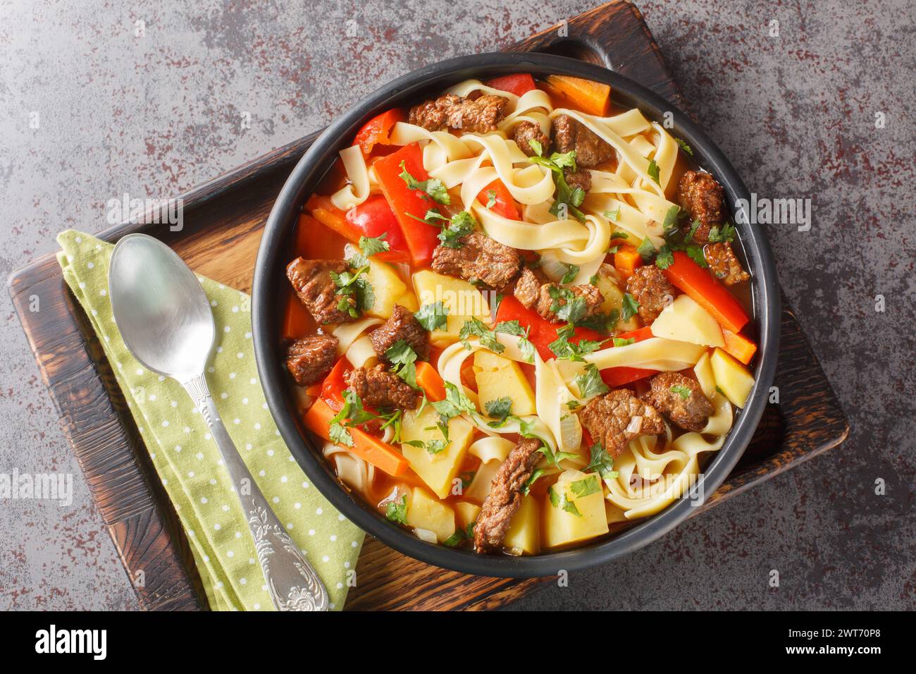 Asiatische Lagman-Suppe mit Lamm, hausgemachten Nudeln und Gemüse in der Nähe auf dem Teller auf dem Holzbrett. Horizontale Draufsicht von oben Stockfoto