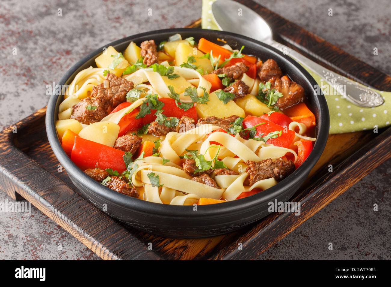 Asiatische Lagman-Suppe mit Lamm, hausgemachten Nudeln und Gemüse in der Nähe auf dem Teller auf dem Holzbrett. Horizontal Stockfoto