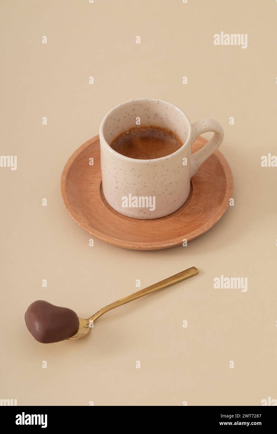 Romantisches Layout mit einer Tasse Kaffee und Schokoladenherz auf pastellfarbenem beigem Hintergrund. Minimales Konzept. Kreativer trendiger Kaffee mit Liebe. Stockfoto