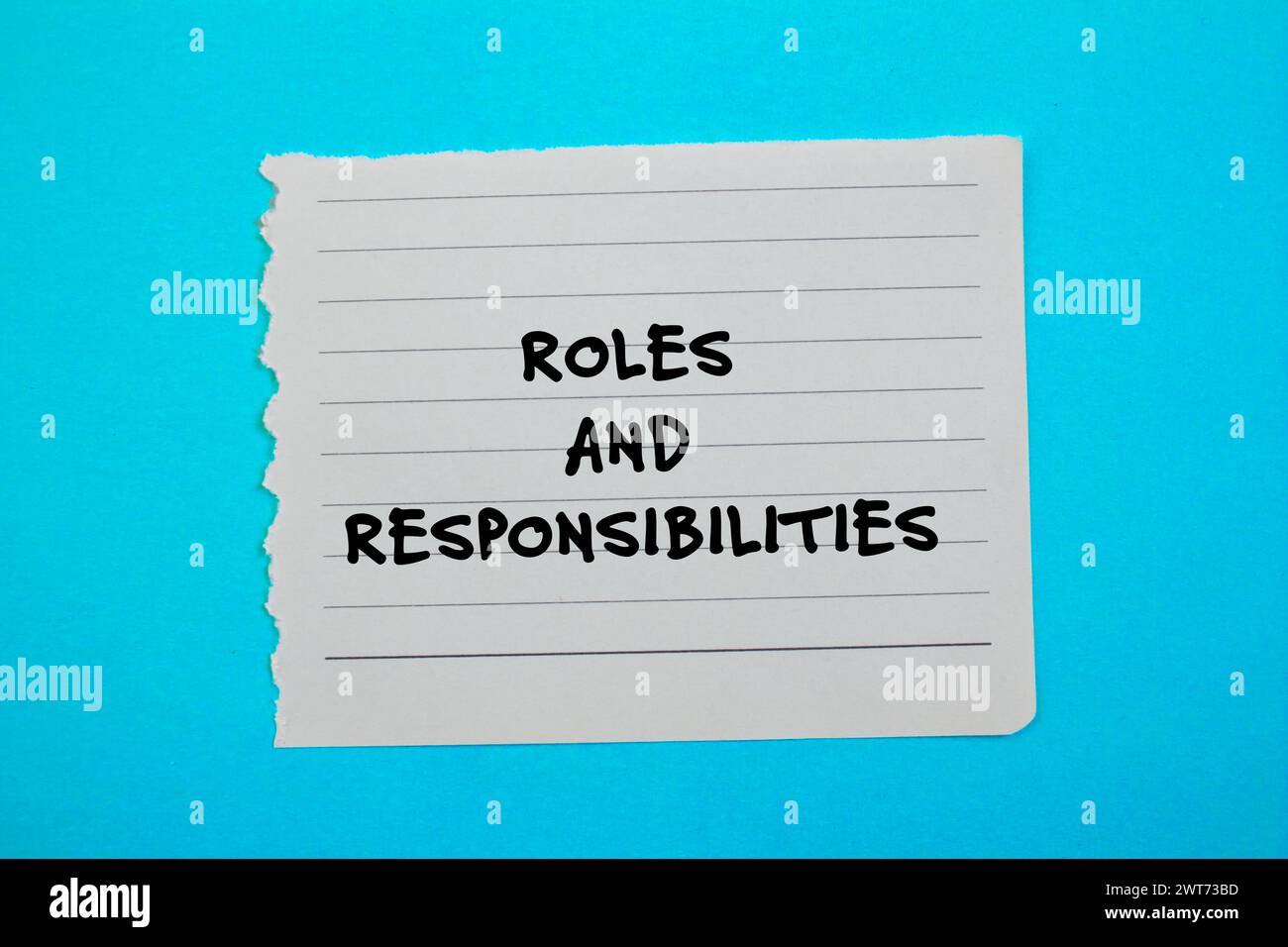 Wörter für Rollen und Verantwortlichkeiten auf gerissenem Papier mit blauem Hintergrund. Konzeptsymbol. Kopierbereich. Stockfoto