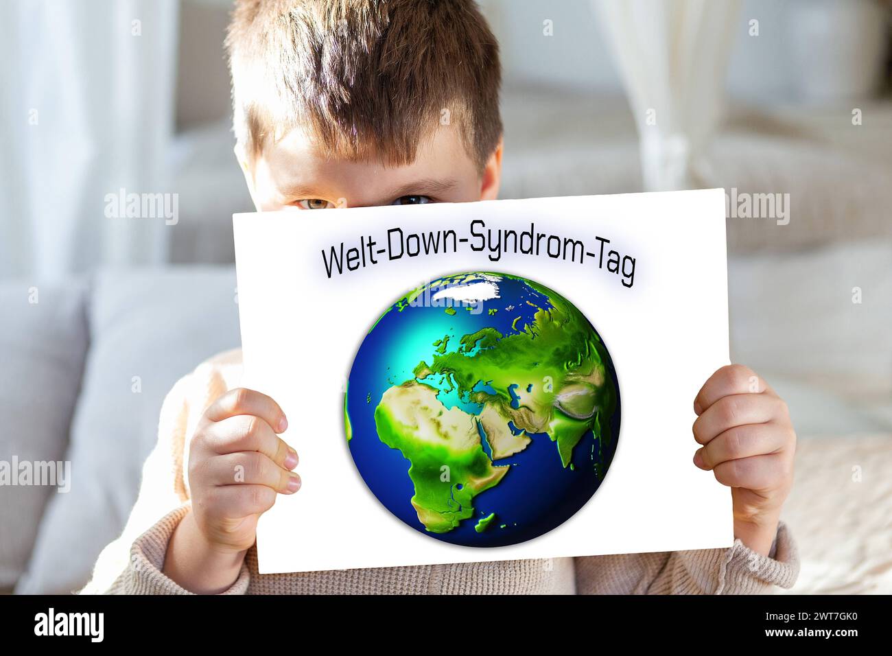 16. März 2024: Kind hält ein Schild mit einem Globus und den Worten: World Down Syndrome Day. PHOTOMONTAGE *** Kind hält ein Schild mit Weltkugel und dem Schriftzug: Welt-Down-Syndrom-Tag. FOTOMONTAGE Stockfoto