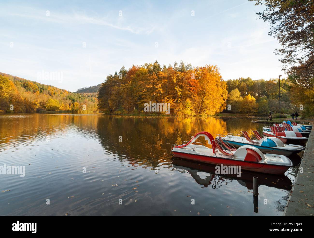 Thalersee zur goldenen Stunde im Oktober. Bootsverleih in der Nähe des Weges um den See. Herbstwald rund um den See in hügeliger Landschaft. Stockfoto