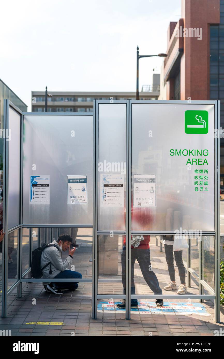 Ausgewiesener Raucherbereich auf der Straße vor dem Bahnhof in Akashi City in Japan. Ein matter Bildschirm, der das Rauchen mit etwas Privatsphäre bietet. Stockfoto