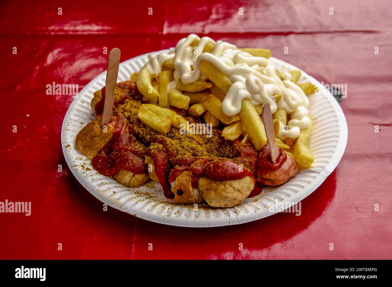 Ein typischer Berliner Snack: currywurst und Pommes mit Mayonaise auf einem Holzteller auf rotem Tischtuch Stockfoto