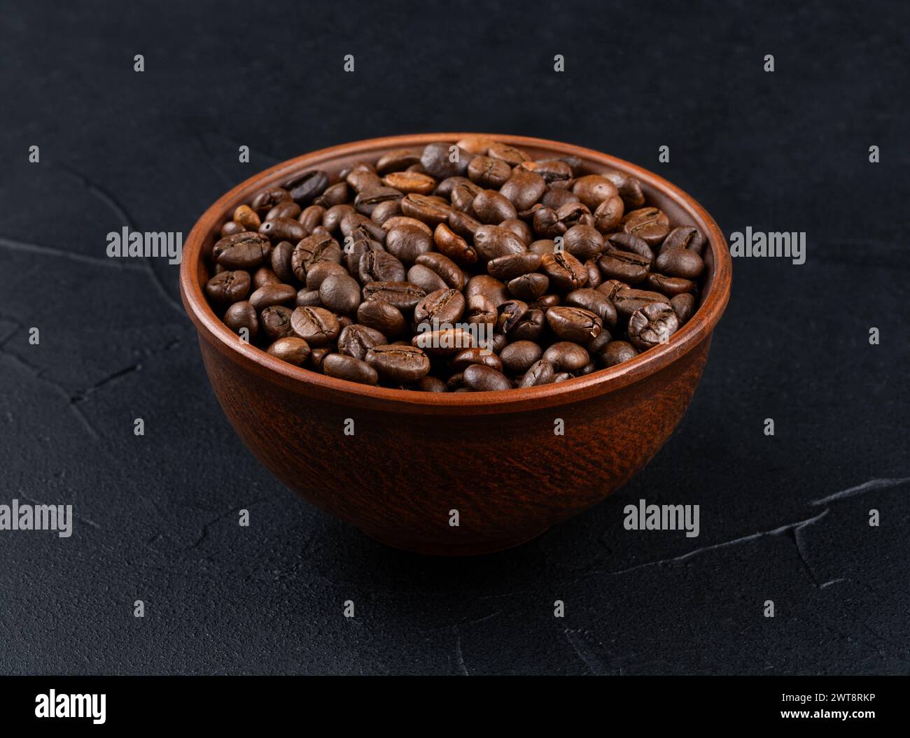 Schüssel voller gerösteter Arabica-Kaffeebohnen auf dunklem Hintergrund Stockfoto