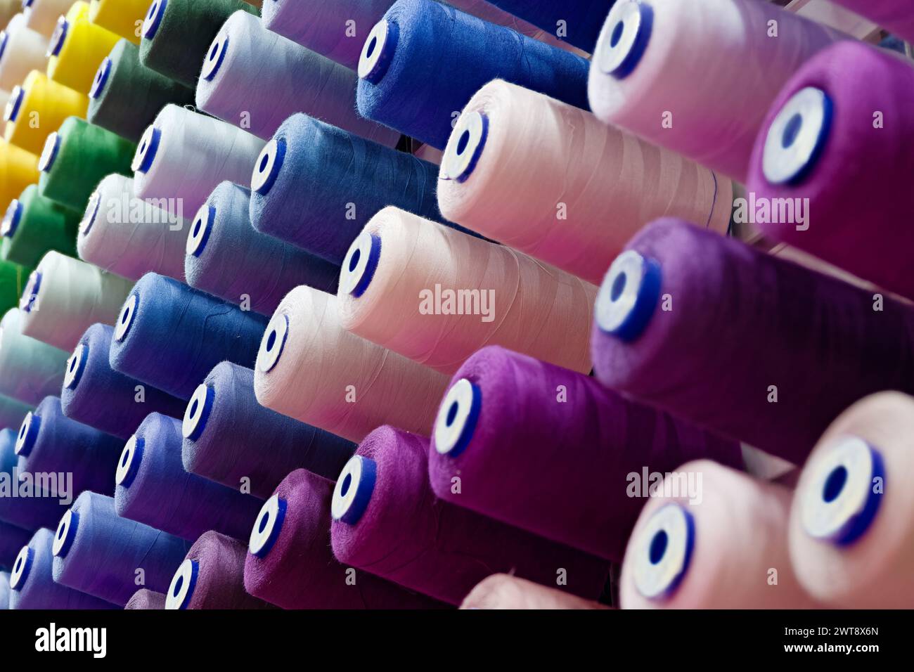 Verschiedene Spulen aus mehrfarbigen Baumwollfäden, abstrakter Hintergrund der Textilindustrie Stockfoto