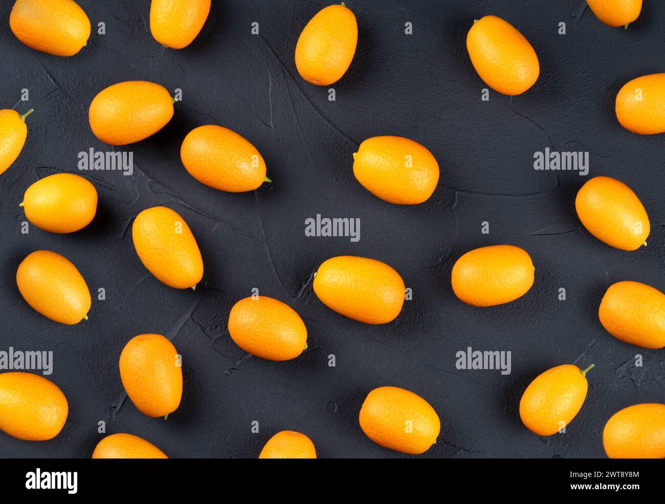 Verstreute frische Kumquat-Früchte auf dunklem Hintergrund, Draufsicht Stockfoto