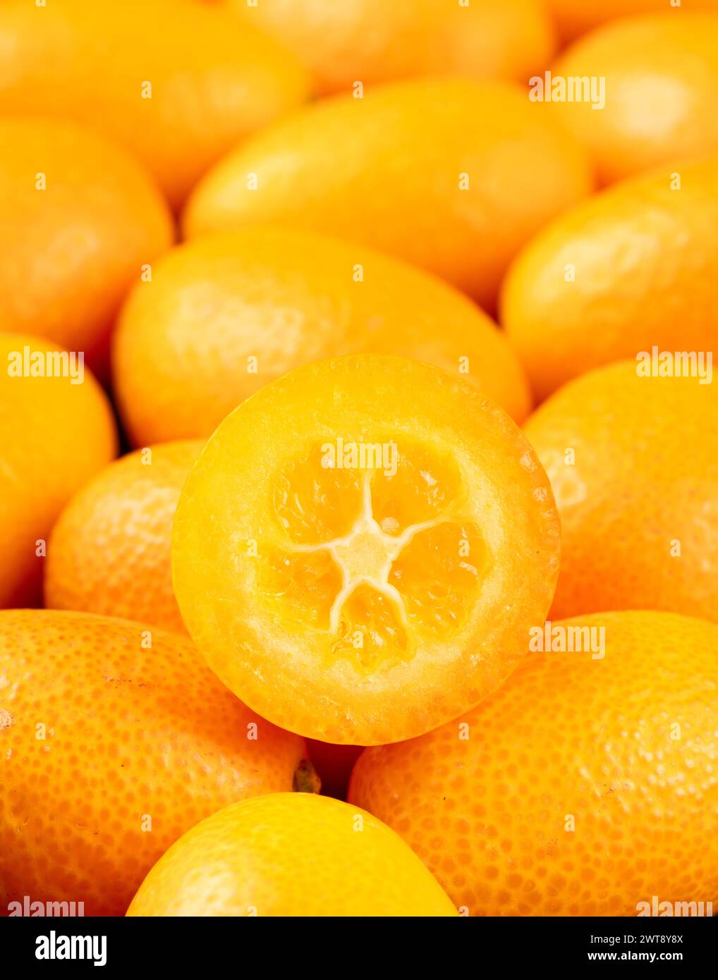 Saftige Hälfte eines Kumquats auf einem Haufen Früchte aus nächster Nähe Stockfoto