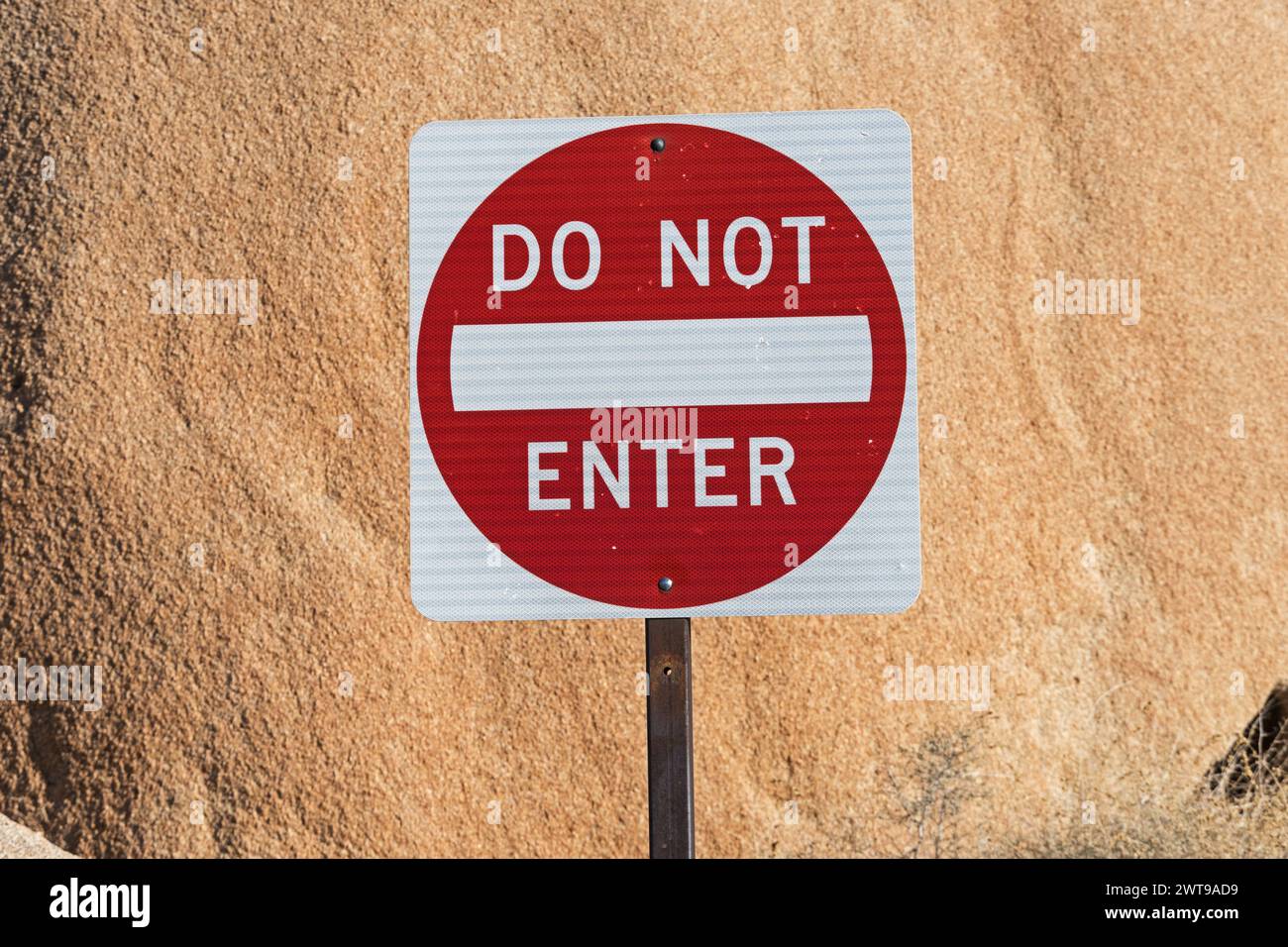 Rot und weiß nicht in das Straßenschild auf dem Metallpfosten vor einem großen Felsen einsteigen Stockfoto