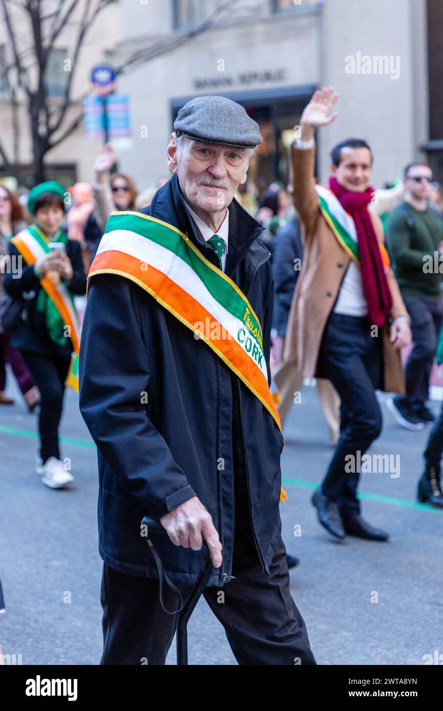 New York, NY, USA. März 2024. Irisch-amerikanische Kontingente starteten von der New Yorker St. Patrick's Day Parade zu den Klängen zahlreicher Pfeifenbänder und bejubelt von den Zuschauern, von denen viele in Grün bedeckt sind. Ein Mann in einer Tweed-Stoffmütze und mit einem Gehstock mit dem County Cork P.B.&P. Association of New York. Quelle: Ed Lefkowicz/Alamy Live News Stockfoto